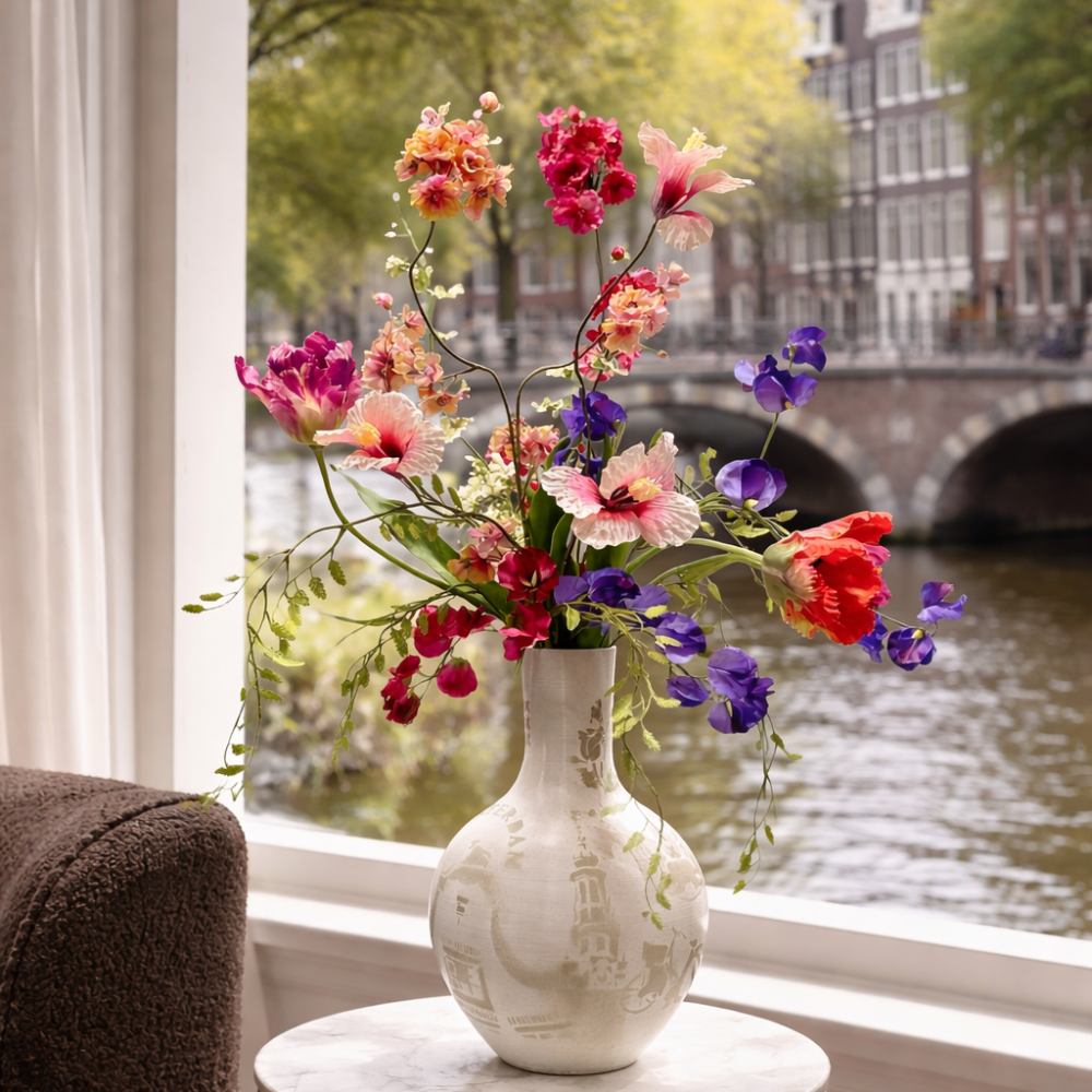 Vaas met Amsterdamgrafitti gespote met kleurrijke zijden bloemen erin. De grachten van Amsterdam op de achtergrond